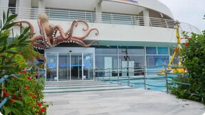 A modern building with the sign "CRET Aquarium." - CRETA GUEST HOUSE ARXONTIKO  15 min to golf club  and 15 minutes to the beach ! (Smari)