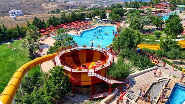 A resort with a large swimming pool, a water slide, and a beach area with umbrellas. - CRETA GUEST HOUSE ARXONTIKO  15 min to golf club  and 15 minutes to the beach ! (Smari)