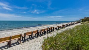 A beach with rows of wooden benches facing the ocean.