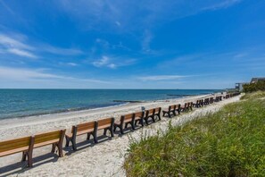 A beach with rows of wooden benches facing the ocean. - Luxury Waterfront Home w/ Heated Pool and Hot Tub (Yarmouth)