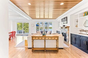 Amplia sala de estar con techo de madera, un sofá blanco, una mesa de centro de madera y vistas al exterior.