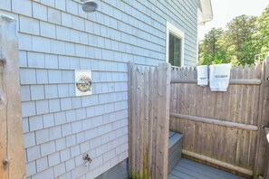 A wooden deck with a metal gate, a metal faucet, and a wooden fence with towels hanging on it. - Luxury Waterfront Home w/ Heated Pool and Hot Tub (Yarmouth)