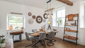 A dining area with a wooden table, chairs, and a bookshelf. - Old Watermill (Grange-over-Sands)