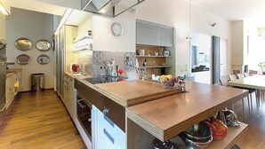 Una cocina moderna con una isla central, electrodomésticos integrados y un comedor con una mesa grande.