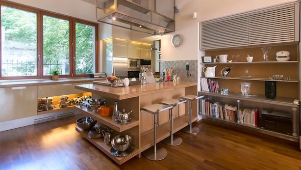 Una cocina moderna con una isla central, electrodomésticos de acero inoxidable y una estantería empotrada.