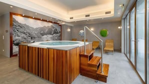 Moderni spa-alue, jossa on puinen poreallas, portaikko ja suuri ikkuna, josta avautuu näkymä ulos.