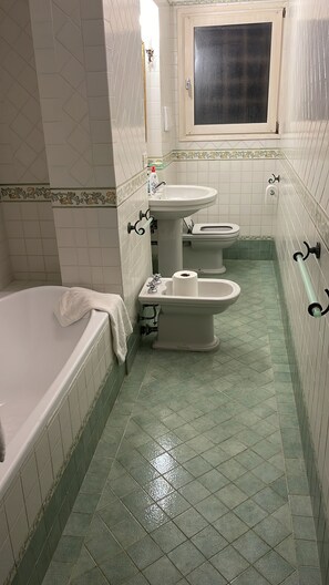 A bathroom with a bathtub, two sinks, and two toilets. - LIONS VENICE Guest House (Venice)