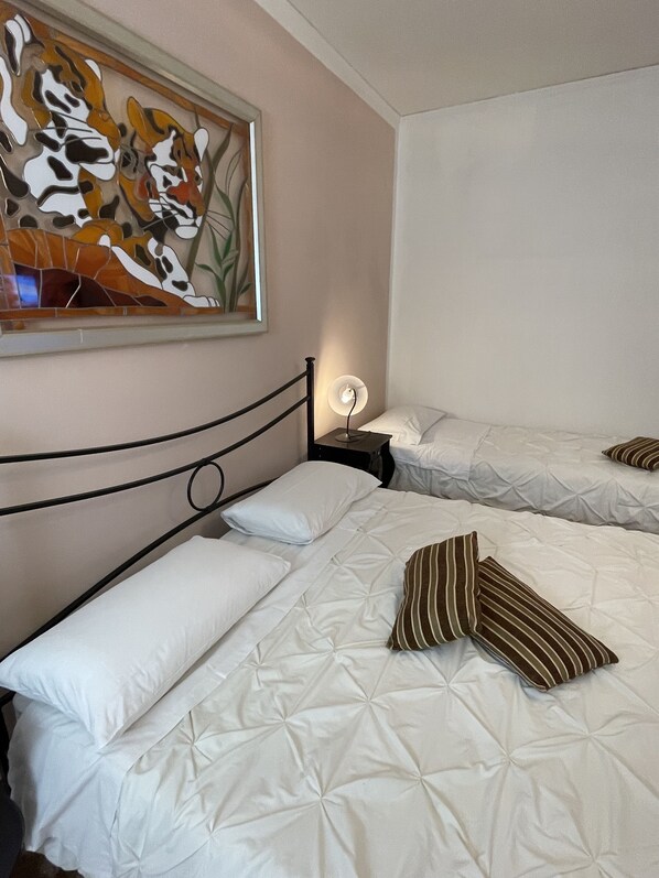 A hotel room with two beds, a nightstand with a lamp, and a wall-mounted artwork. - LIONS VENICE Guest House (Venice)