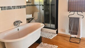 Un baño moderno con una bañera independiente, una ducha con cerramiento de vidrio y suelo de madera.