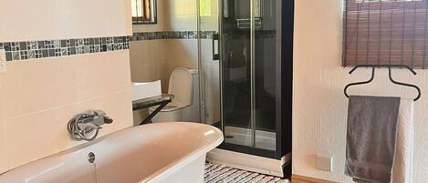 Un baño moderno con una bañera independiente, una ducha con cerramiento de vidrio y suelo de madera.