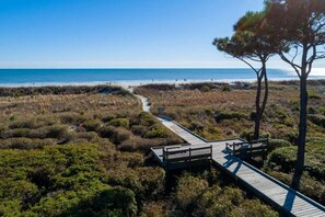 A wooden boardwalk leading to a beach with a clear view of the ocean.