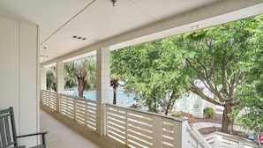 A covered balcony with a pool view, white railings, and a bench. - 529 Sunsuite (Fripp Island)