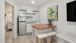 A compact kitchen with white cabinetry, a microwave, a stove, and a small bar area with stools. - 529 Sunsuite (Fripp Island)