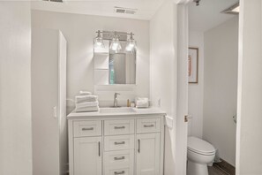 A bathroom with a white vanity, a mirror, and a toilet. - 529 Sunsuite (Fripp Island)