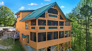 A multi-story log cabin with a green roof, large windows, and a stone foundation. - Moonlight Pines Lodge- 4bdrm, Pool Table, Mountain View (Sevierville)
