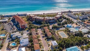An aerial view of a coastal resort with multiple buildings, a beach, and a tennis court. - 1BA/1BA Miramar Beach, Inquire for Monthly Rates (Miramar Beach)