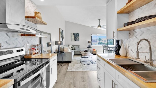 A modern kitchen with a built-in oven, a sink, and wooden shelves. - 1BA/1BA Miramar Beach, Inquire for Monthly Rates (Miramar Beach)