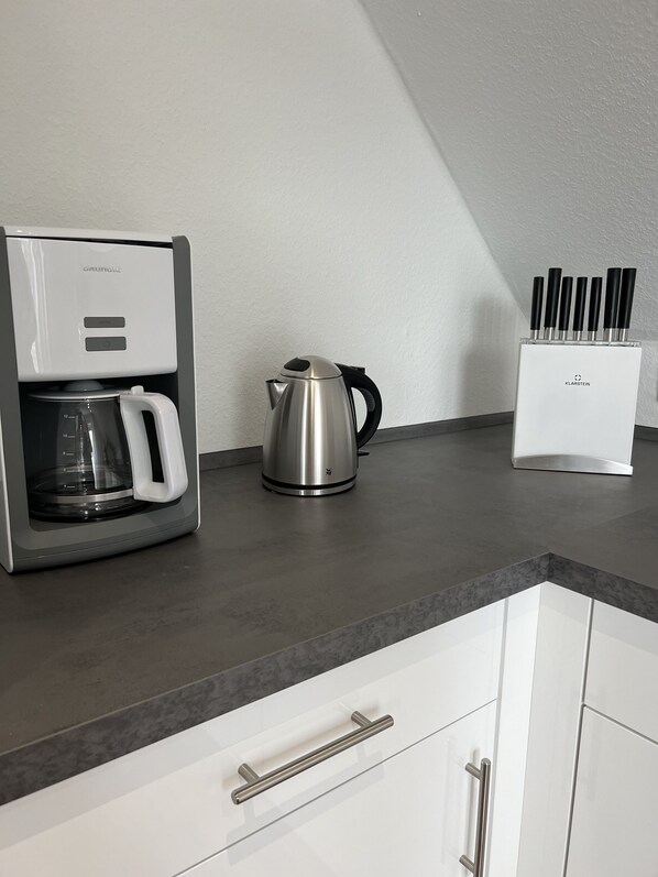 A kitchen with a coffee maker, a kettle, and a knife block on the countertop. - Ferienwohnung Meischen (Bad Zwischenahn)