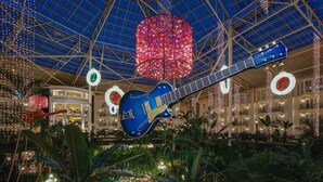 A large atrium with a blue guitar sculpture, a glass ceiling, and a 'Garden Conservatory' sign.