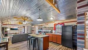 A spacious kitchen with a large island, wooden cabinets, and a black refrigerator.