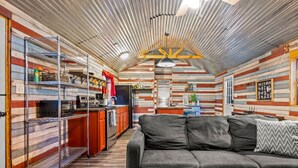 A compact, rustic cabin interior with a kitchenette, a sofa, and a dining area.
