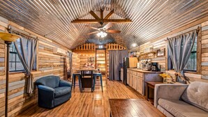 Un intérieur de chalet chaleureux avec des murs en bois, un coin repas, une cuisine et des sièges.