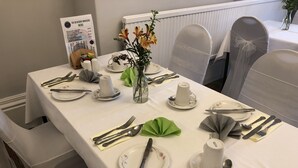 Une table à manger élégamment dressée, avec une nappe blanche, des assiettes, des couverts et un présentoir à menus.