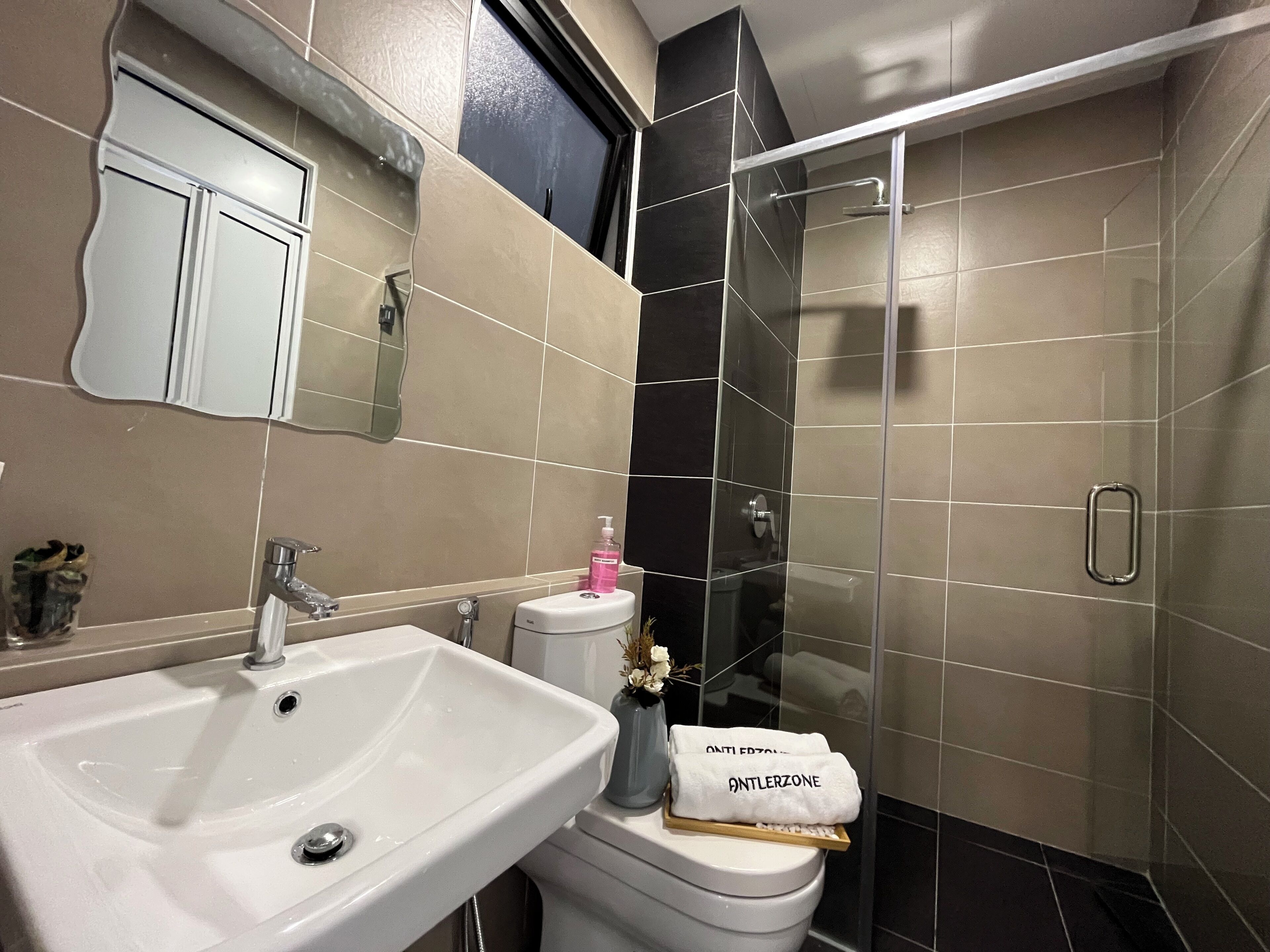 Un baño moderno con un lavabo blanco, un inodoro y una ducha con cerramiento de vidrio.