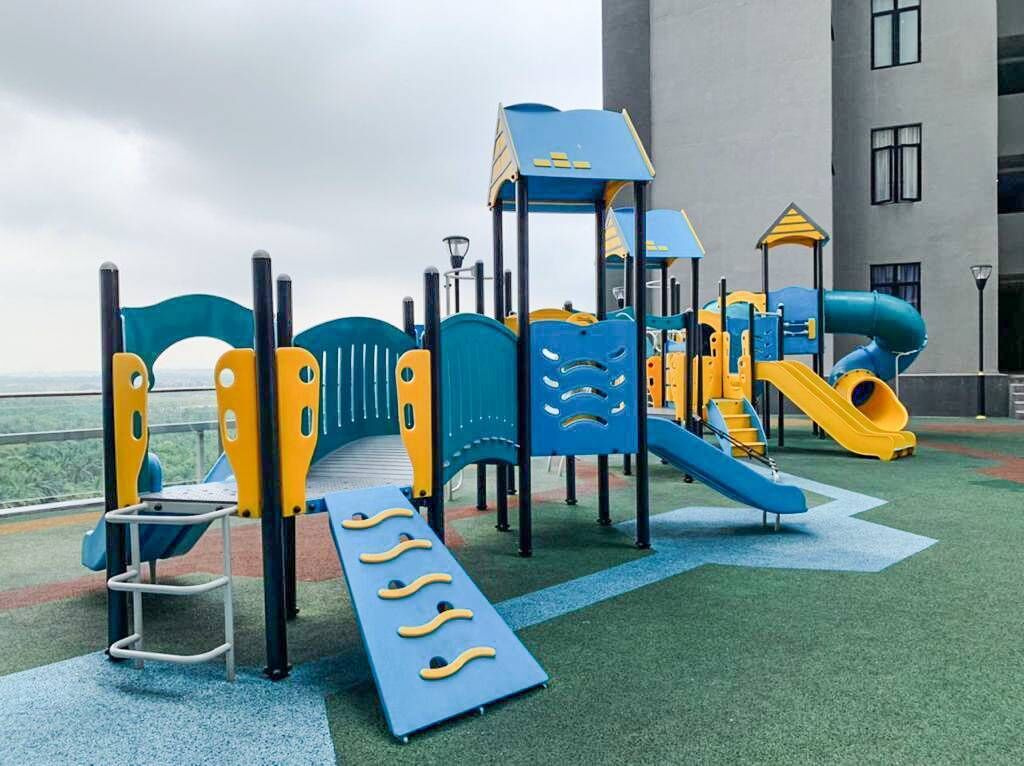 A playground with slides and climbing structures, set against a building backdrop.