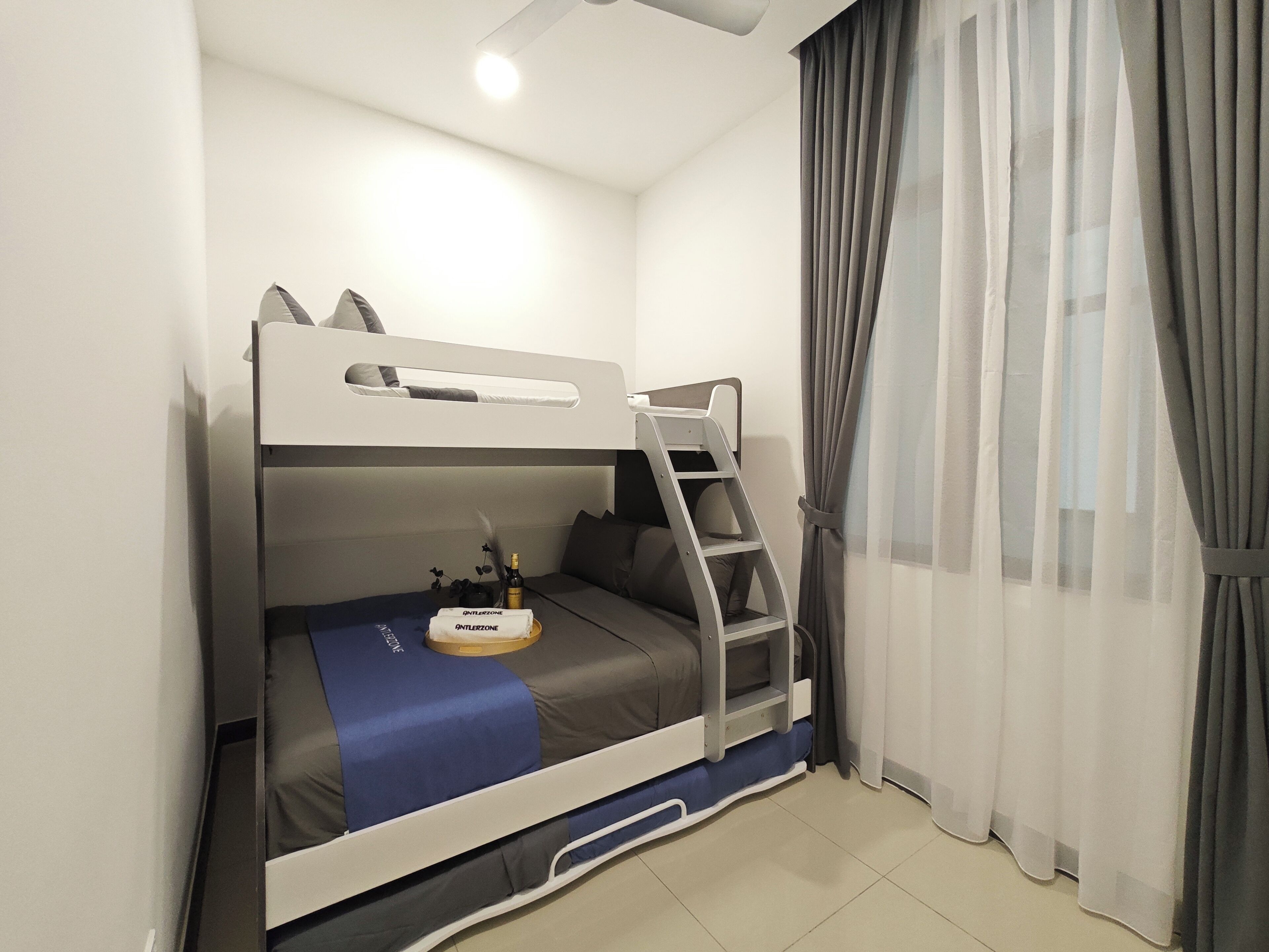 A bunk bed room with a ladder, a bottle of wine, and a small table.