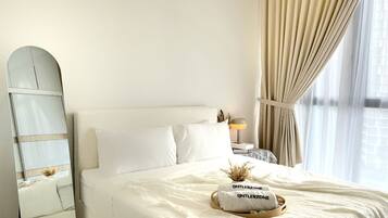 A neatly made bed with white linens, a bedside lamp, and a decorative pillow with text.