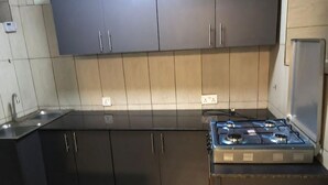 Eine moderne Küche mit dunklen Schränken, einer Spüle aus Edelstahl und einem Gasherd.