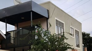 Ein modernes, zweigeschossiges Haus mit flachem Dach, Satellitenschüssel und einem kleinen Balkon.