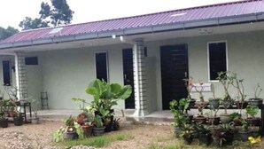 A building with a covered porch, multiple windows, and potted plants.