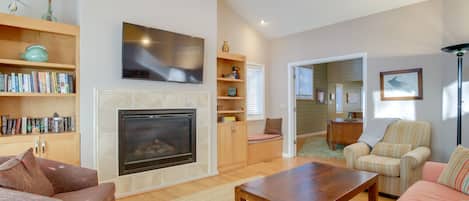 Una sala de estar con chimenea, un televisor montado arriba y una estantería llena de libros.