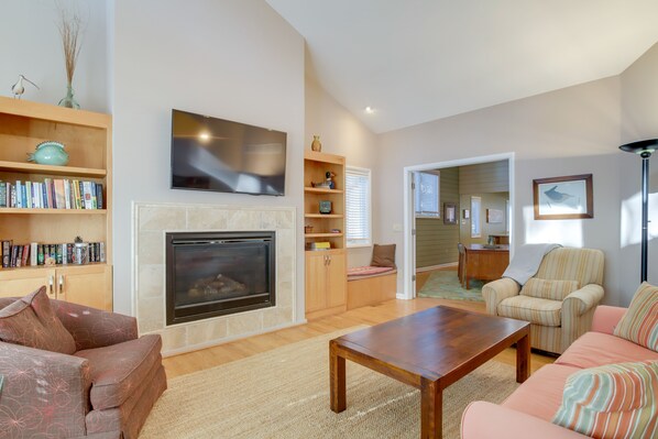 A living room with a fireplace, a television mounted above it, and a bookshelf filled with books.