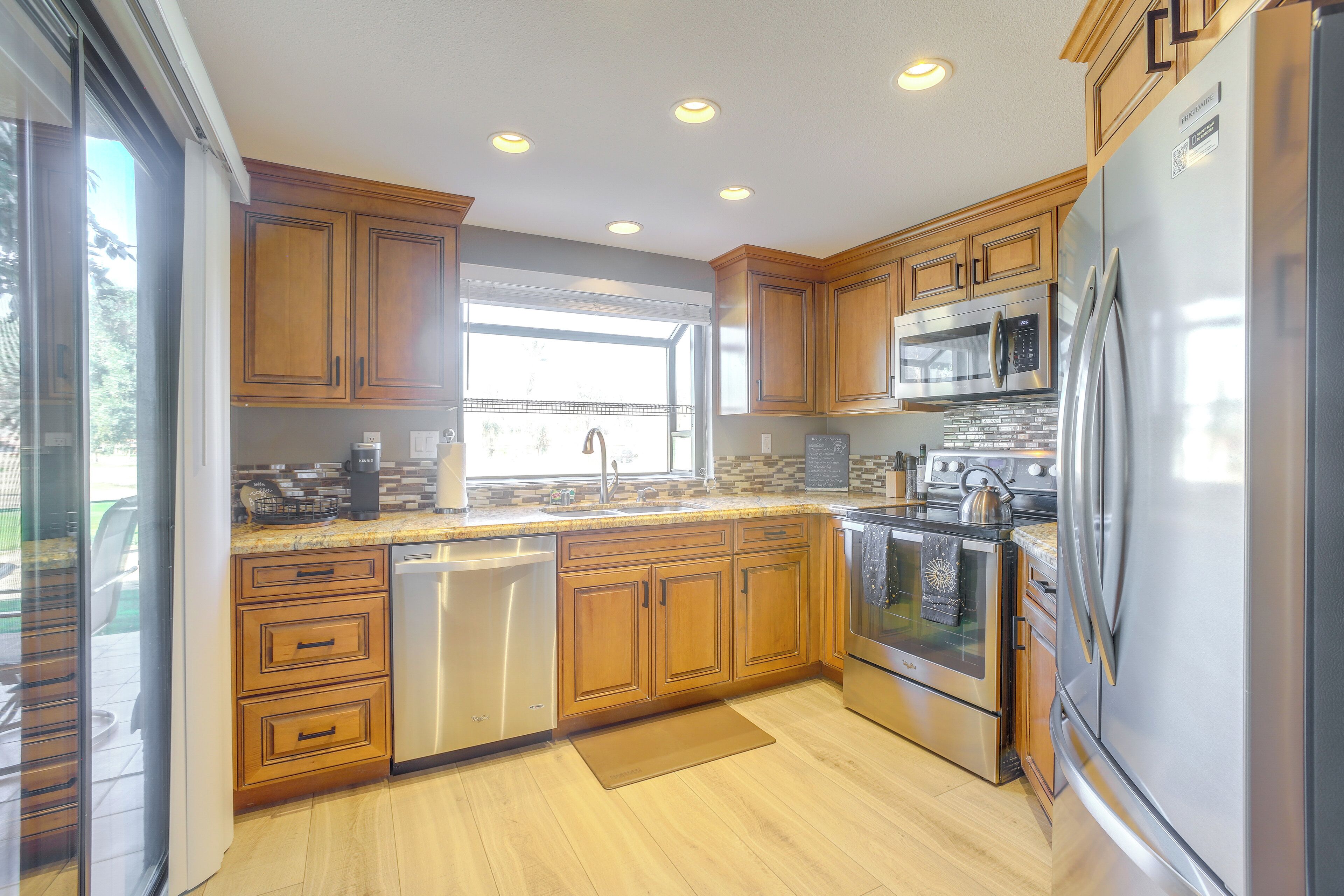 Una cocina moderna con gabinetes de madera, electrodomésticos de acero inoxidable y un amplio ventanal que proporciona luz natural.