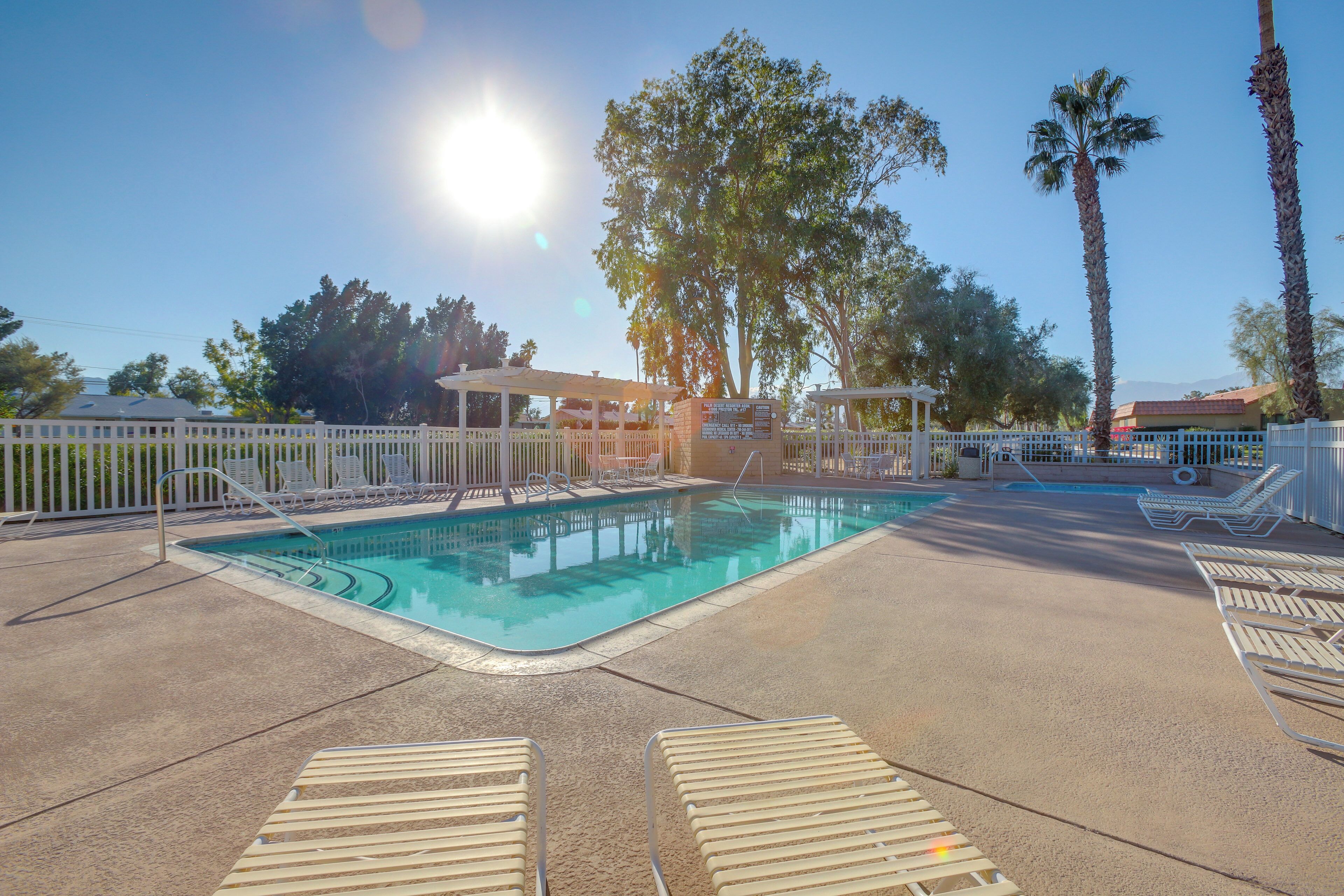 Un espace piscine avec des chaises longues et une terrasse entourée d’une clôture.