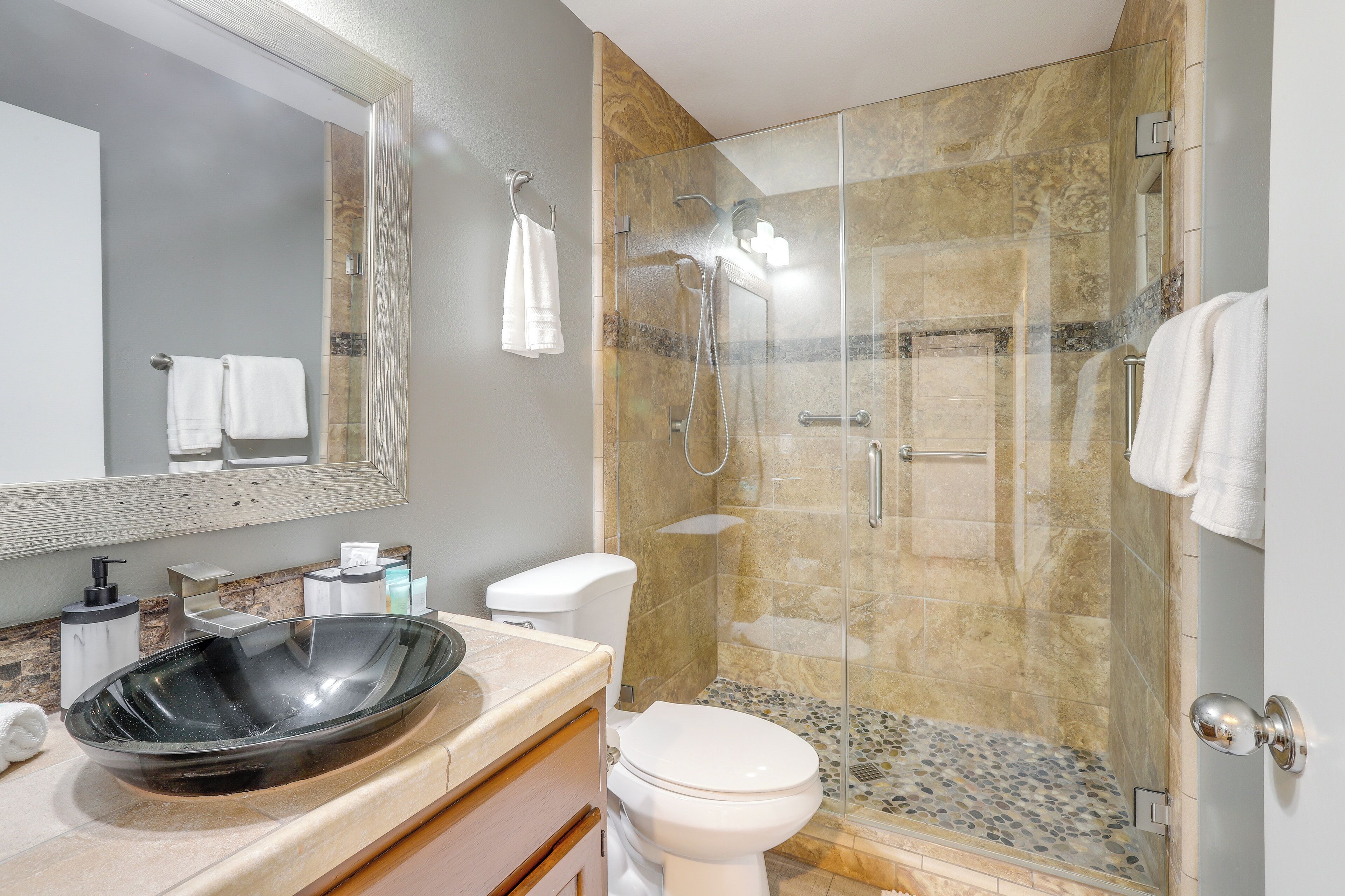 Une salle de bain moderne avec une douche à parois de verre, un grand lavabo ovale et des toilettes.