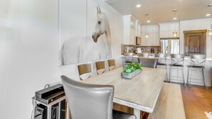 A modern dining area with a large wooden table, metal chairs, and a horse-themed wall mural. - Park City Townhome w/ Hot Tub & Mountain Views! (Kamas)