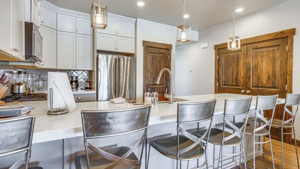 A modern kitchen with white cabinets, stainless steel appliances, and a central island with bar stools. - Park City Townhome w/ Hot Tub & Mountain Views! (Kamas)