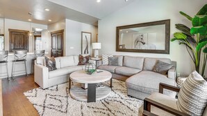 A modern living room with a sectional sofa, a round coffee table, and a large mirror. - Park City Townhome w/ Hot Tub & Mountain Views! (Kamas)