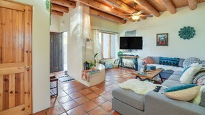 A spacious living area with a wooden ceiling, a grey sofa, a television, and a ceiling fan. - Bright Santa Fe Condo ~ Half-mi to Meow Wolf! (Santa Fe)