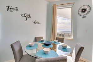 A dining area with a glass table, four chairs, and decorative wall art.