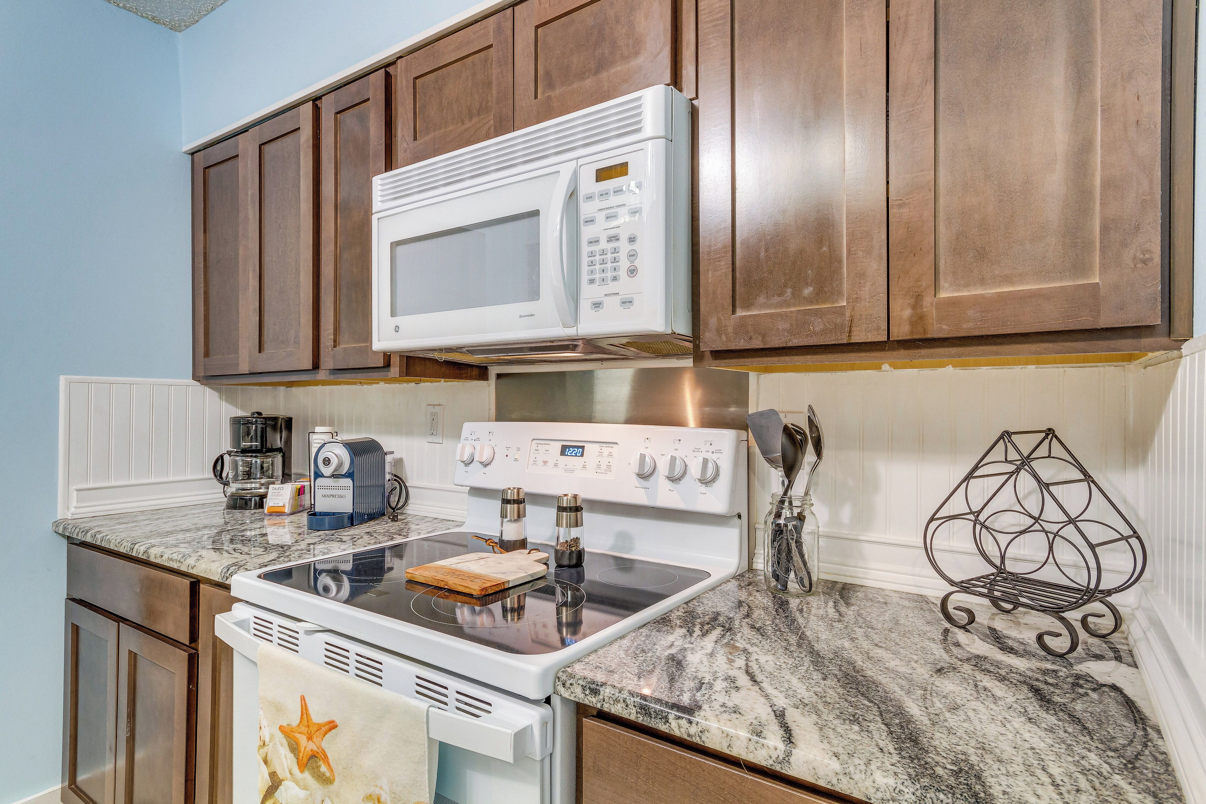 A kitchen with a white microwave, stove, and coffee maker.