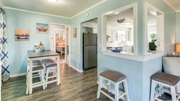 A kitchen with a refrigerator, a dining table with stools, and a bar area with stools.