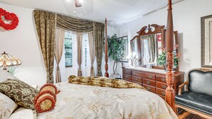 A bedroom with a four-poster bed, a wooden dresser, a mirror, and a ceiling fan. - Tampa Area Home w/ Indoor Pool, Families Welcome! (Brandon)