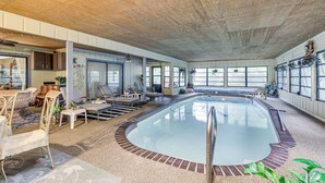 An indoor swimming pool with a wooden ceiling, seating area with chairs and tables, and large windows. - Tampa Area Home w/ Indoor Pool, Families Welcome! (Brandon)