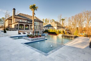 A large house with a swimming pool, stone exterior, and a well-maintained garden. - Sprawling Suwanee Home: Theater, Pool, Hot Tub! (Suwanee)