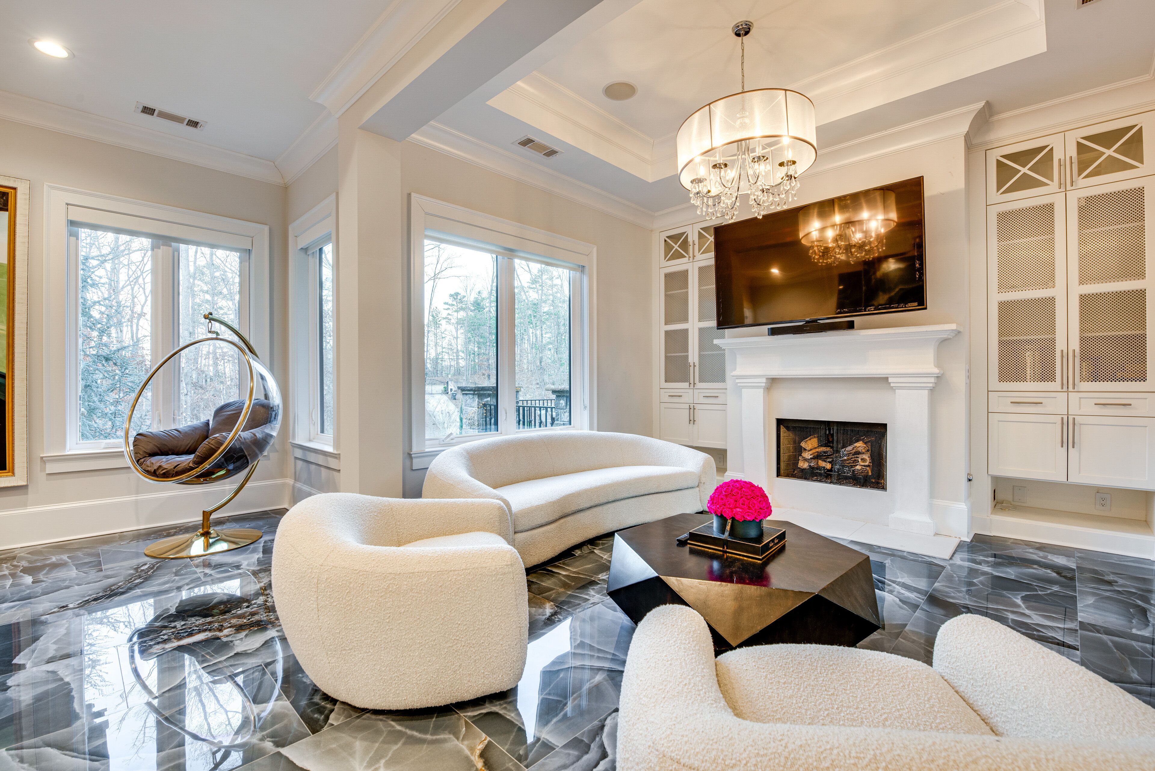 A spacious living room with a curved white sofa, a round chair, a coffee table, and a fireplace.